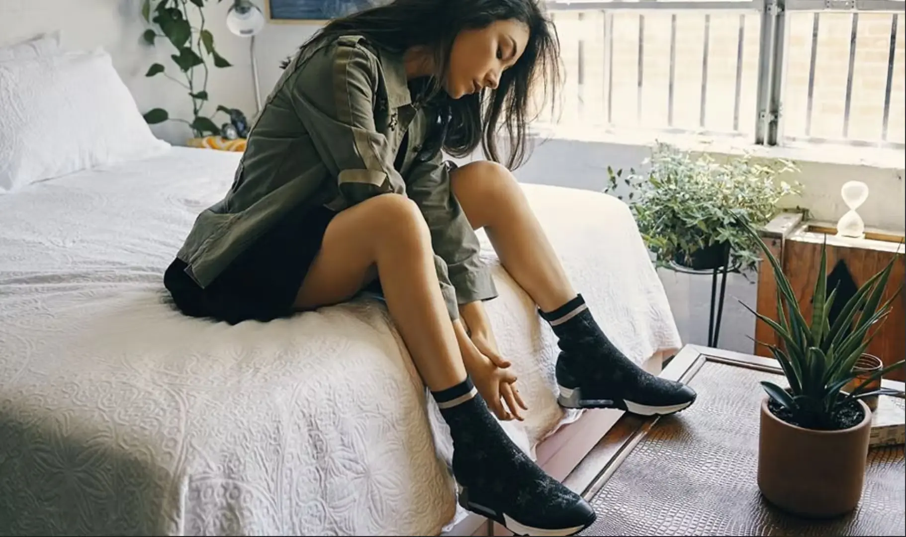 Woman sitting on a bed, who is wearing green