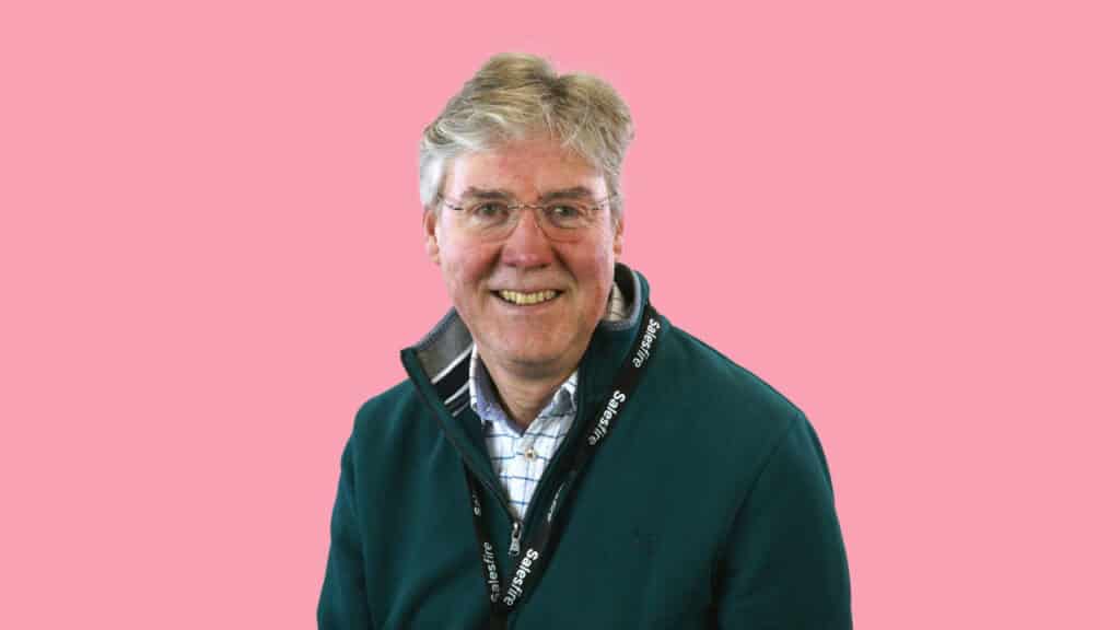 A smiling man with a black jacket in a pink background