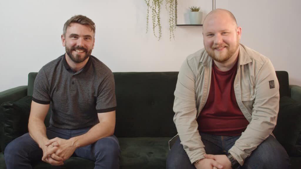 2 men sitting on a sofa smiling